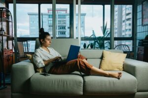 A woman in her laptop working cozily in her home at her living room - VirtualPro Solutions