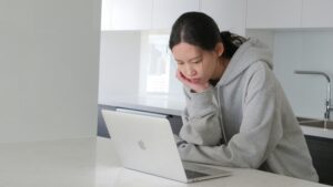 A woman looking closely at her laptop while at home - Virtual Pro Solutions
